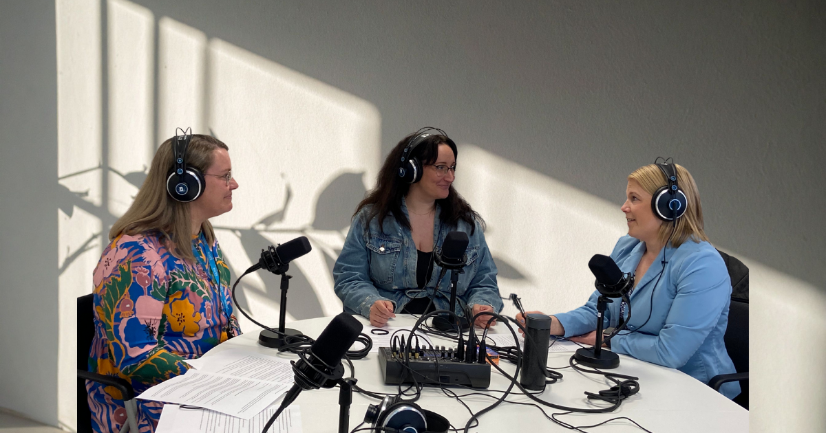 Petra Sippola, Mari Viljanen ja Minttu Porri istuvat pyöreän pöydän äärellä. Kaikilla on podcastiin tarvittavat kuulokkeet ja mikrofoni.