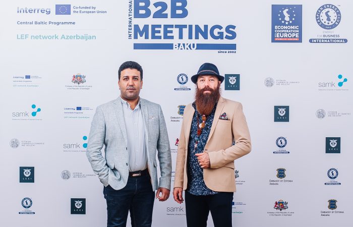 Two men standing in front of a meeting wall.